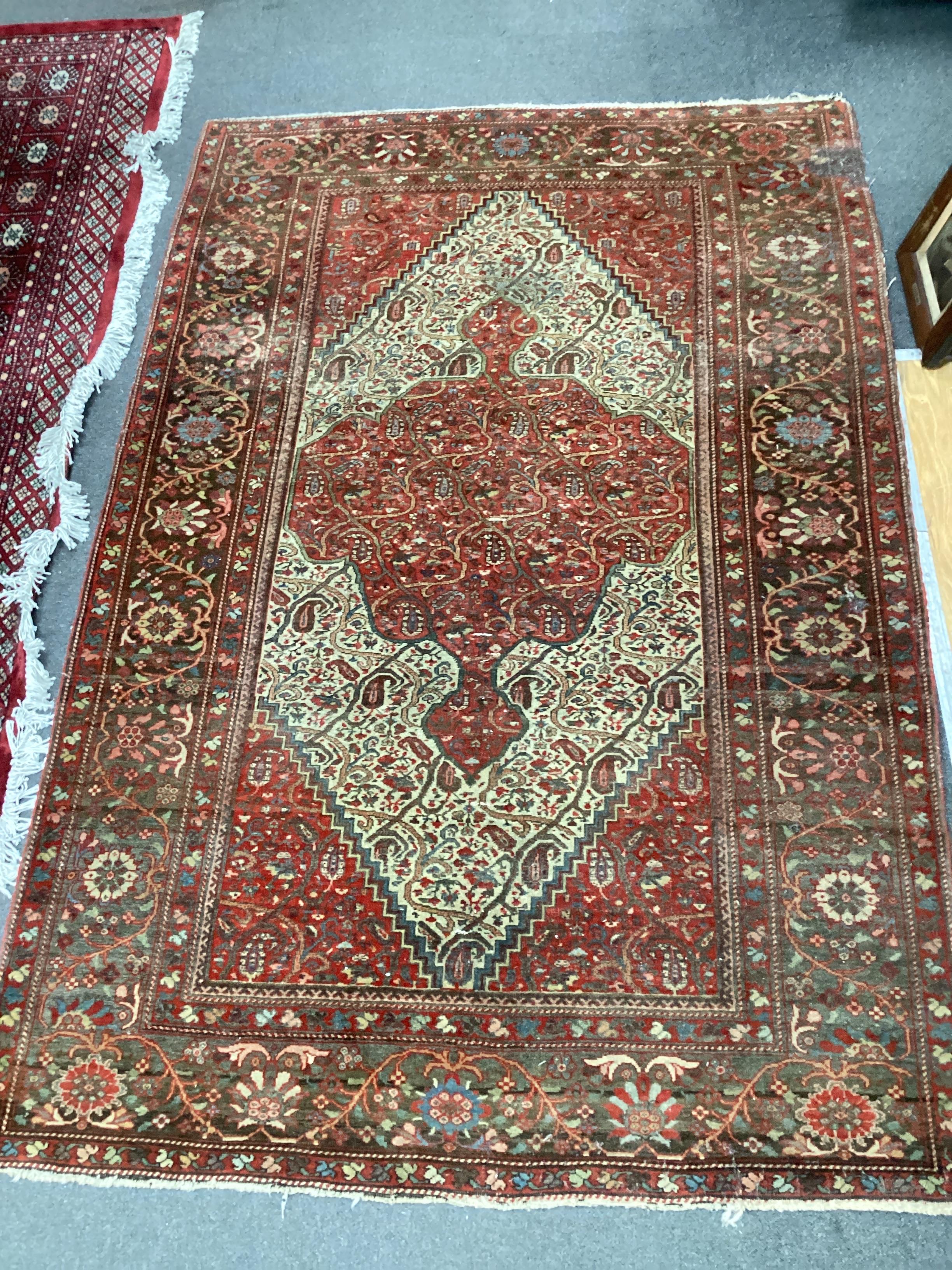 An Isphahan red and cream medallion rug, enclosed by a border of trailing stylised foliage, 200cm x 132cm